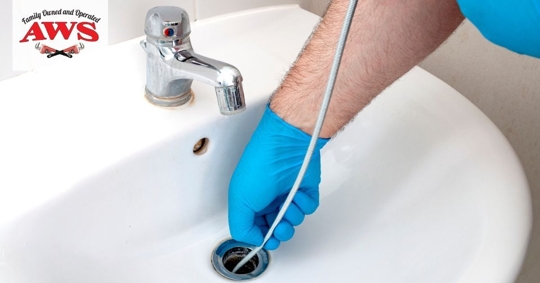 Person using a plumbing snake in sink