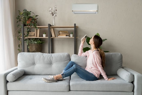 Woman adjusting the air conditioning in her apartment.